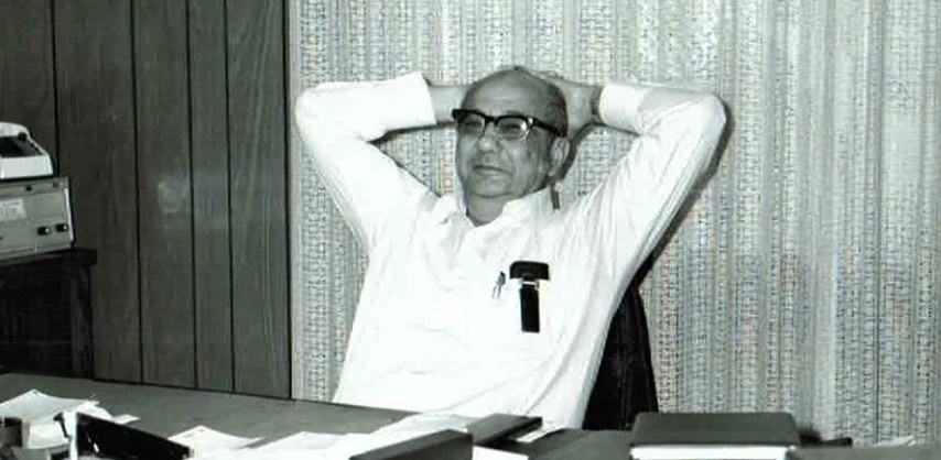 Black-and-white photo from GAR's early years: a man in a white shirt leaning back at his office desk